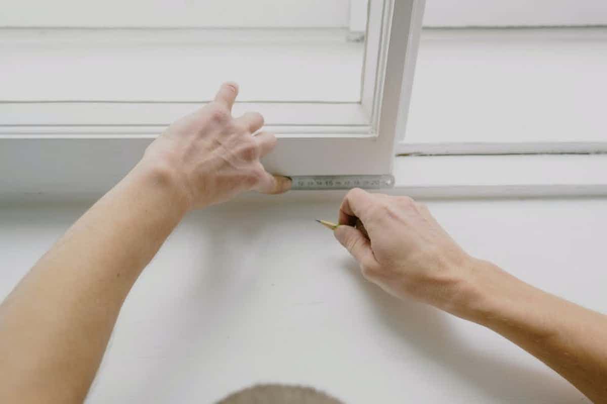 person showing how to measure a window for replacement